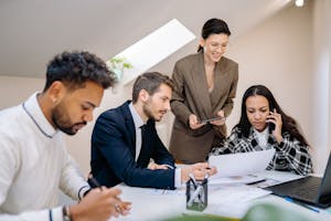 Group of professionals collaborating in a bright, modern office environment with digital devices.
